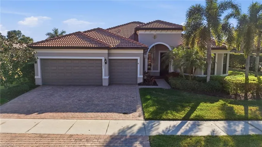 Mediterranean / spanish home with a garage, stucco siding, decorative driveway, a front yard, and a tile roof