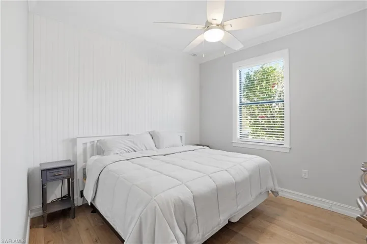 Bedroom with ornamental molding, wood finished floors, and a ceiling fan