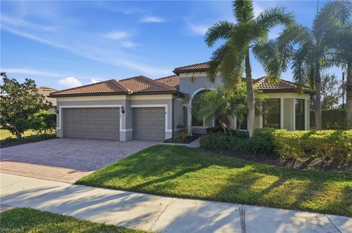 Mediterranean / spanish-style home with a garage, driveway, stucco siding, a front yard, and a tiled roof