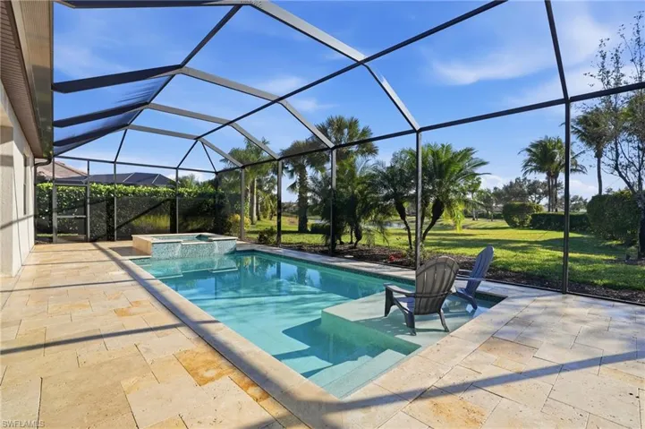 Integrated pool / hot tub featuring a sunroom, a private patio area, cage enclosure, and a nicely landscaped lawn.