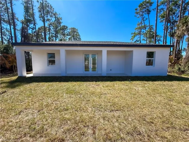 Rear view of house featuring a yard and stucco siding