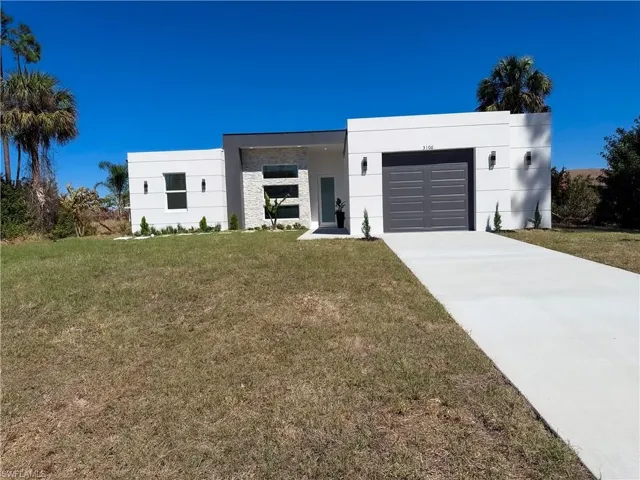 Modern home with a front lawn, a garage, stucco siding, and driveway