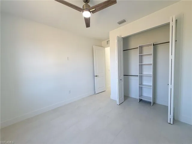 Unfurnished bedroom featuring light flooring, a ceiling fan, and a closet