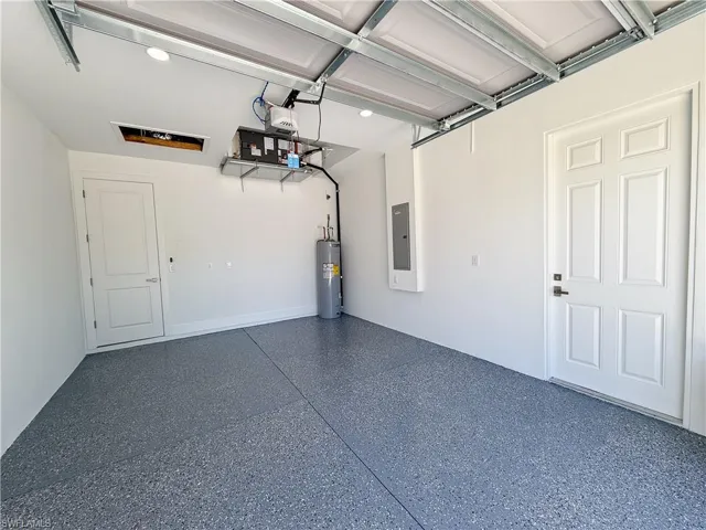 Garage with electric water heater, electric panel, and recessed lighting
