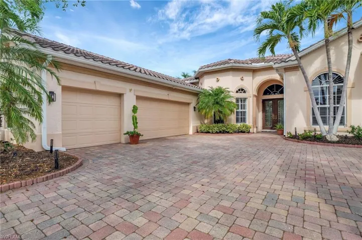 Mediterranean / spanish-style home with a tile roof, french doors, stucco siding, an attached garage, and decorative driveway