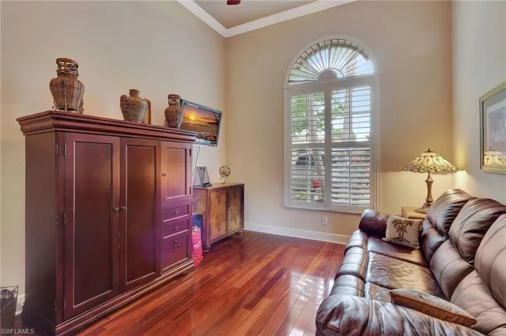 Living room featuring dark wood-style flooring, ornamental molding, and baseboards