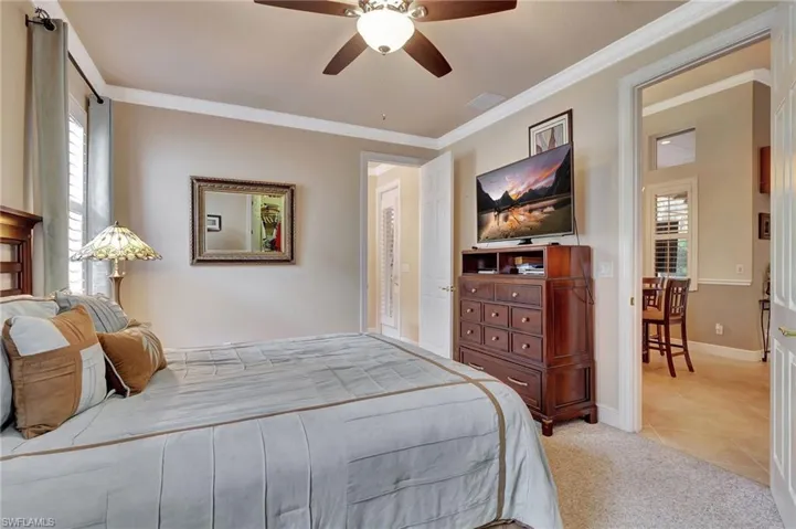 Bedroom featuring carpet flooring, ornamental molding, baseboards, tile patterned floors, and a ceiling fan