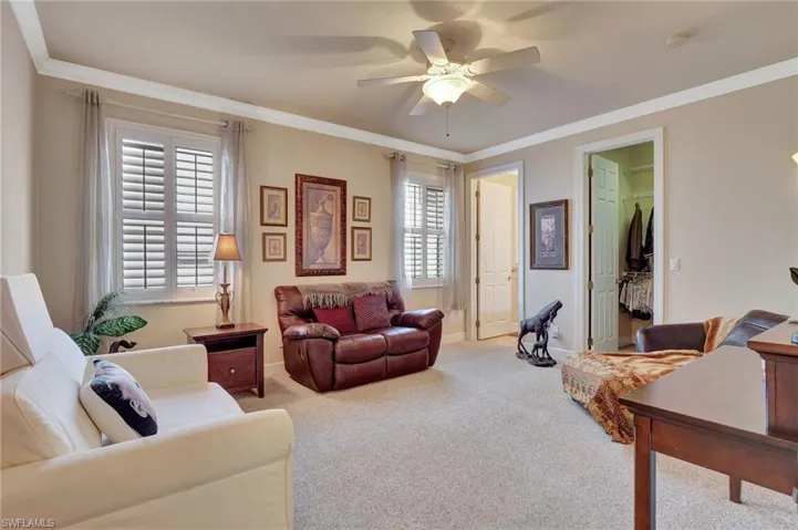 Living room featuring baseboards, carpet flooring, ceiling fan, and crown molding