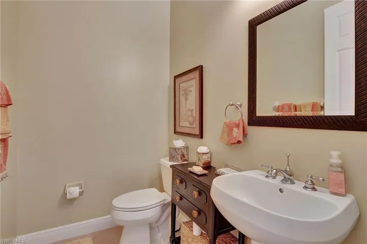 Bathroom featuring toilet, a sink, tile patterned floors, and baseboards