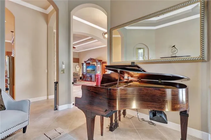 Living area featuring baseboards, crown molding, arched walkways, and light tile patterned floors
