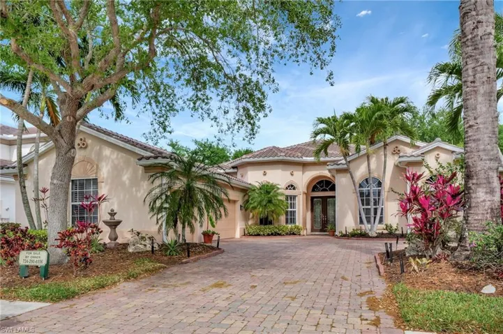 Mediterranean / spanish house with a tile roof, stucco siding, an attached garage, french doors, and decorative driveway