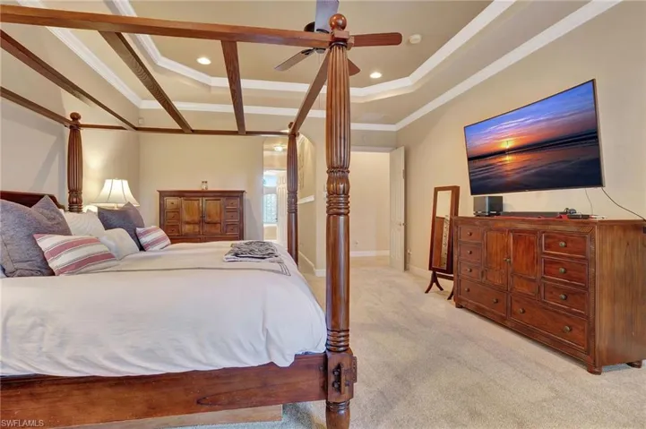 Bedroom with light colored carpet, crown molding, recessed lighting, and a raised ceiling