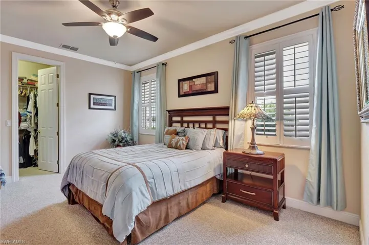 Bedroom with ornamental molding, visible vents, a spacious closet, and light carpet