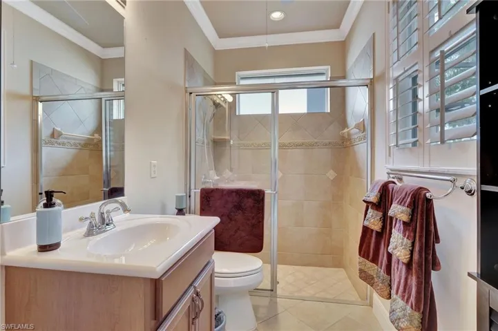 Bathroom featuring a stall shower, vanity, and ornamental molding