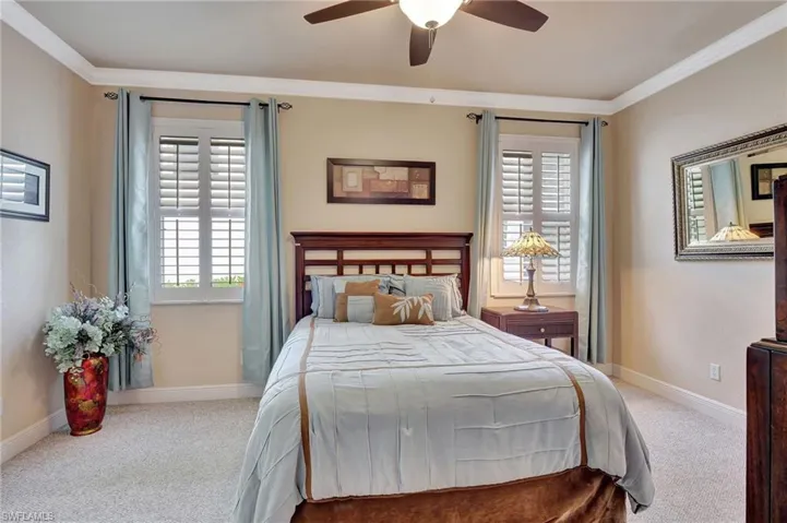 Bedroom with baseboards, crown molding, ceiling fan, and carpet
