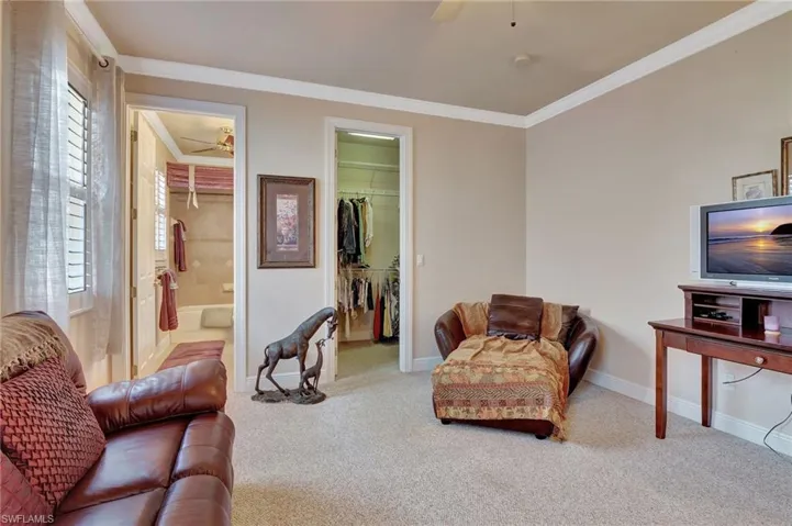 Carpeted living room with baseboards, ornamental molding, and a ceiling fan