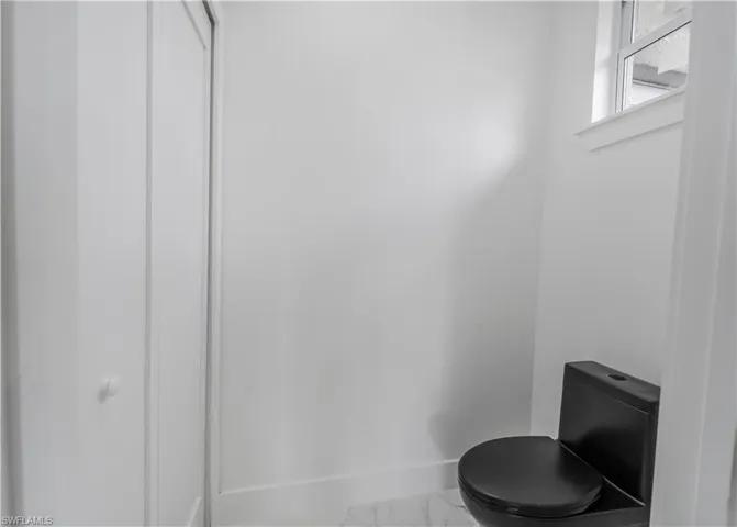 Bathroom with marble finish floor, baseboards, and toilet