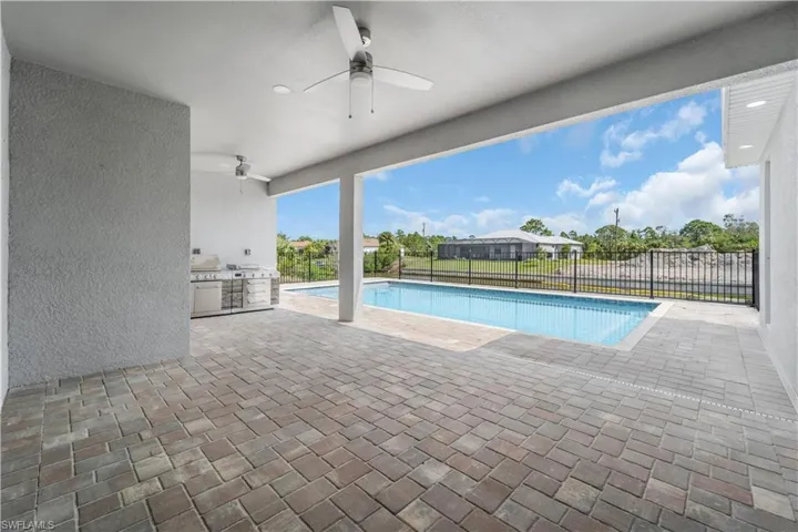View of swimming pool featuring a fenced in pool, a patio, ceiling fan, exterior kitchen, and a fenced backyard