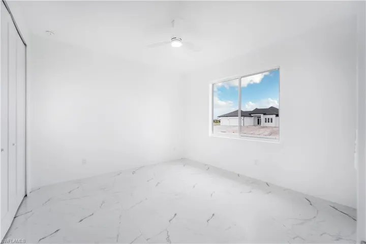 Unfurnished room with marble finish floor and a ceiling fan