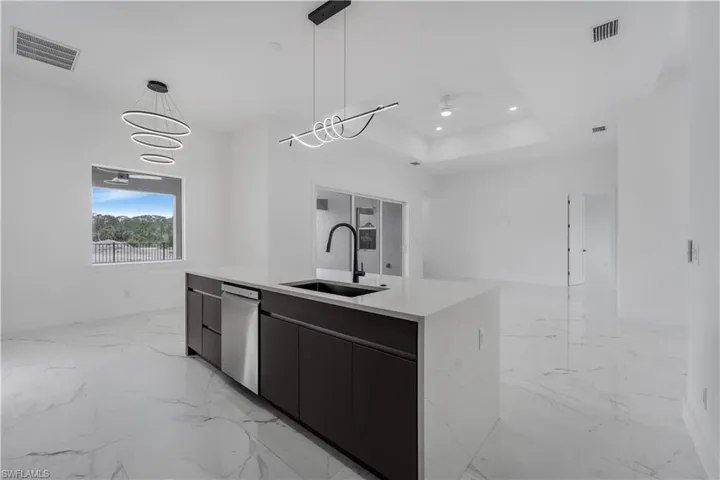 Kitchen with decorative light fixtures, light countertops, a sink, modern cabinets, and dishwasher