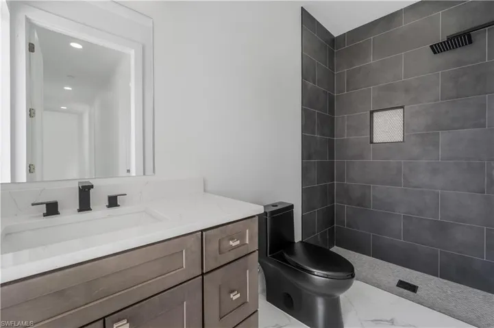 Full bath featuring marble finish floor, toilet, vanity, and a shower stall
