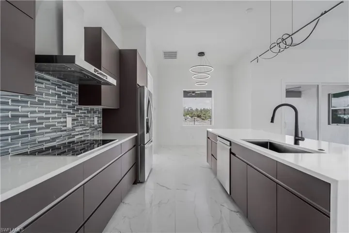 Kitchen with light countertops, hanging light fixtures, modern cabinets, and a sink
