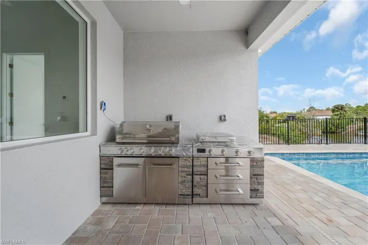 View of patio / terrace featuring a fenced in pool, fence, grilling area, and exterior kitchen