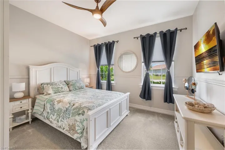 Bedroom featuring multiple windows, ceiling fan, and light colored carpet