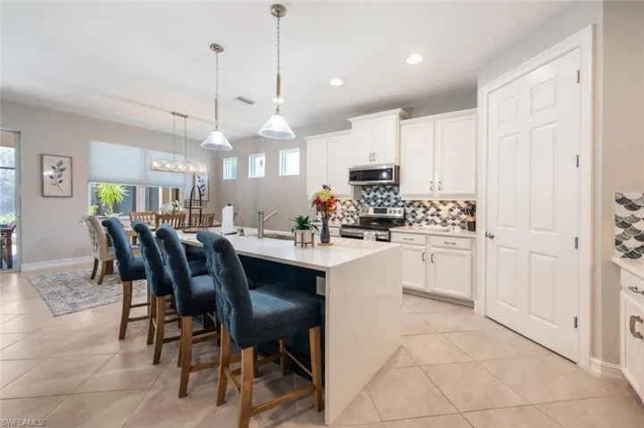 Kitchen featuring plenty of natural light, appliances with stainless steel finishes, backsplash, and a kitchen bar