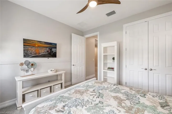 Carpeted bedroom with ceiling fan and a closet