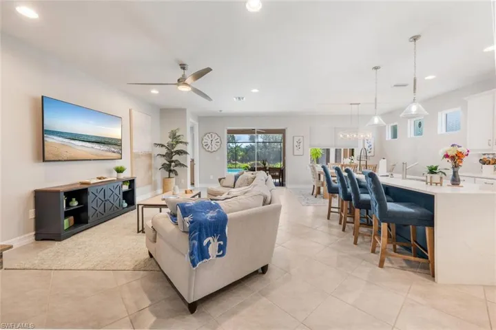 Living room featuring light tile patterned flooring and ceiling fan with notable chandelier