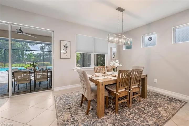 Tiled dining room with ceiling fan with notable chandelier and a wealth of natural light