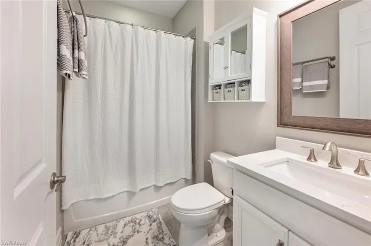 Full bathroom with vanity, shower / bath combo, tile patterned flooring, and toilet