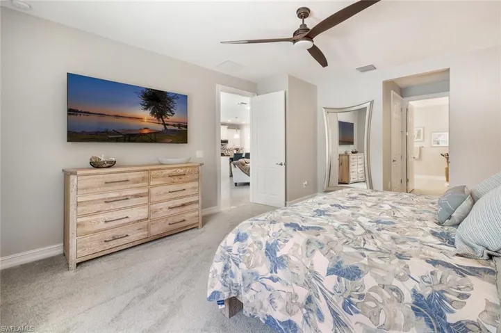 Carpeted bedroom with ensuite bath and ceiling fan
