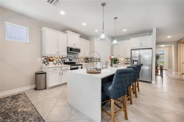 Kitchen with light tile patterned flooring, tasteful backsplash, appliances with stainless steel finishes, and plenty of natural light