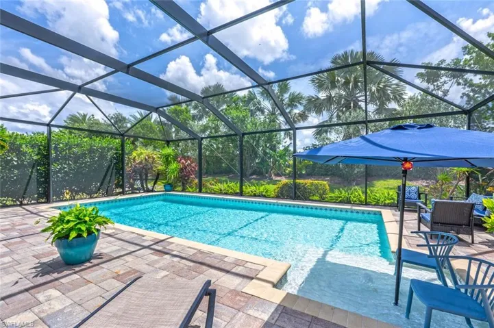 View of pool featuring glass enclosure and a patio area