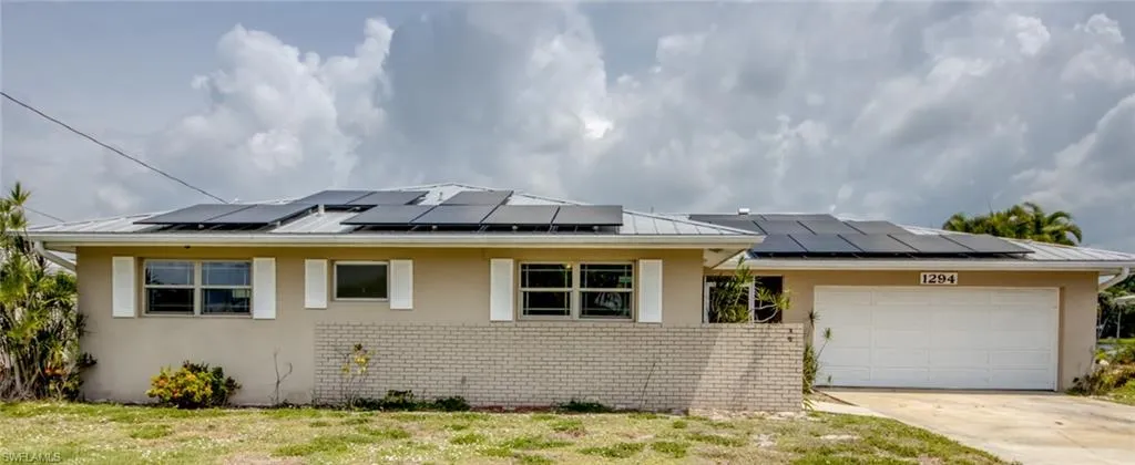 View of front of property featuring a garage and solar panels
