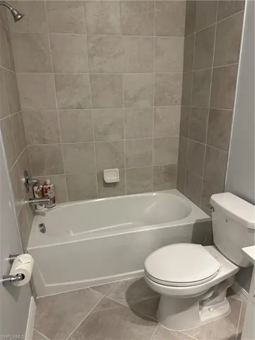 Bathroom featuring tile patterned floors, tiled shower / bath, and toilet.