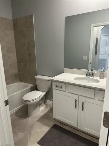 Full bathroom with tile patterned flooring, shower / washtub combination, toilet, and vanity.