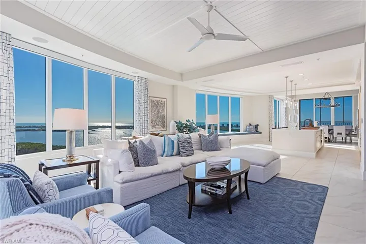 Living area with marble finish flooring, a ceiling fan, a water view, a chandelier, and plenty of natural light