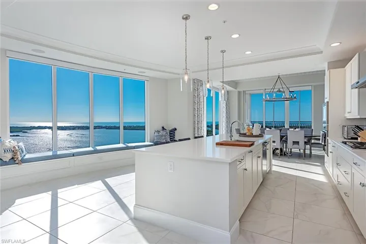 Kitchen featuring white cabinets, hanging light fixtures, a kitchen island with sink, recessed lighting, and a chandelier