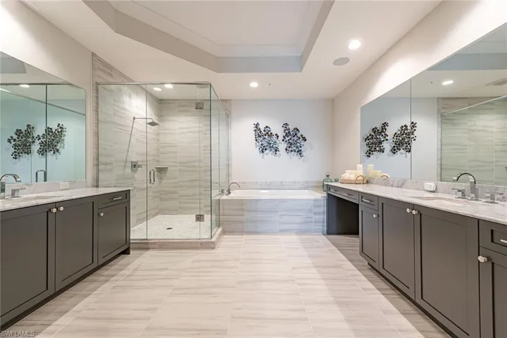 Full bath with two vanities, a shower stall, and a garden tub