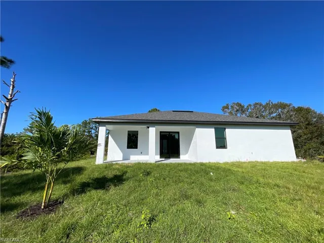 Back of house featuring ceiling fan and a yard