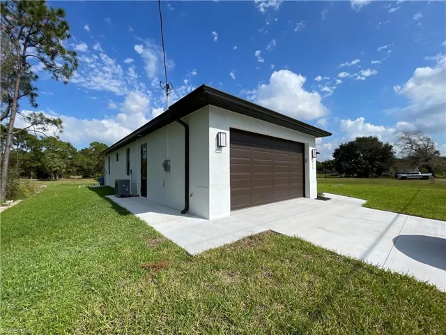 View of property exterior featuring a garage and a yard