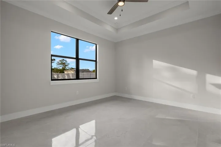 Empty room featuring a tray ceiling, crown molding, and ceiling fan