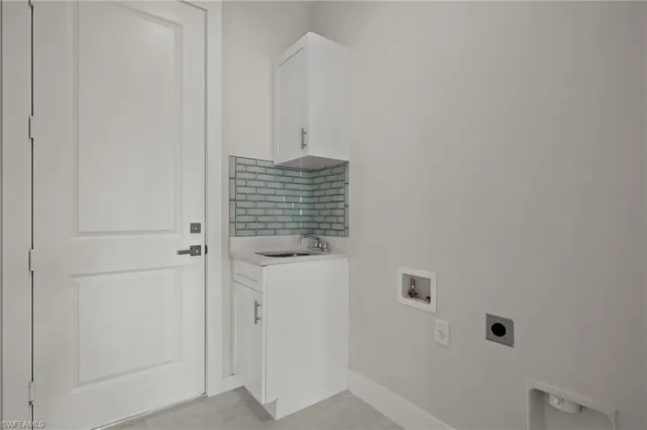 Laundry room with cabinets, sink, washer hookup, light tile patterned floors, and hookup for an electric dryer