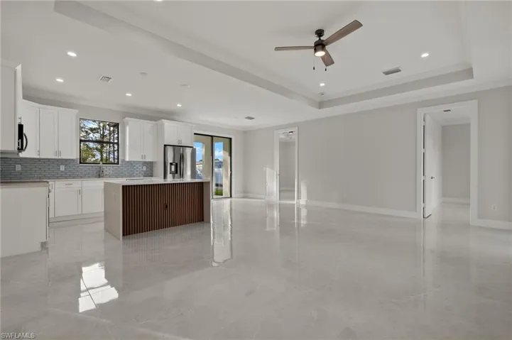 Kitchen featuring white cabinets, stainless steel fridge, a kitchen island, and ceiling fan