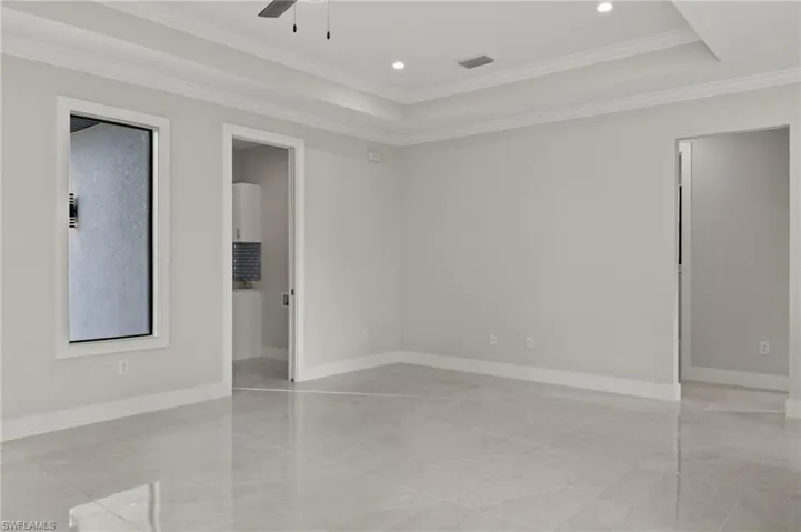 Empty room with ceiling fan, ornamental molding, and a tray ceiling