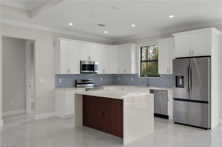 Kitchen featuring a center island, stainless steel appliances, and white cabinetry