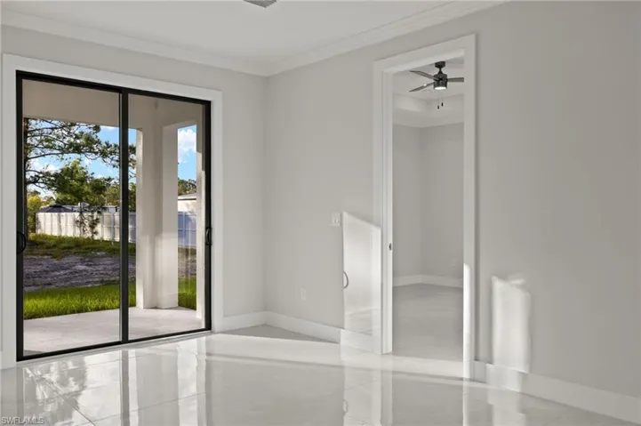 Entryway with ceiling fan, ornamental molding, and light tile patterned floors